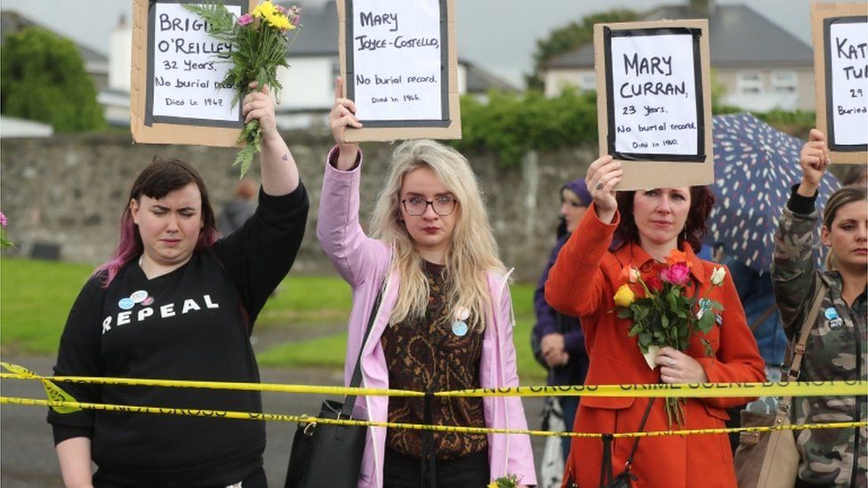 Women hold placards of the names of babies buried at Tuam