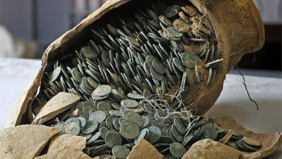 Roman bronze coins held in a cracked jar
