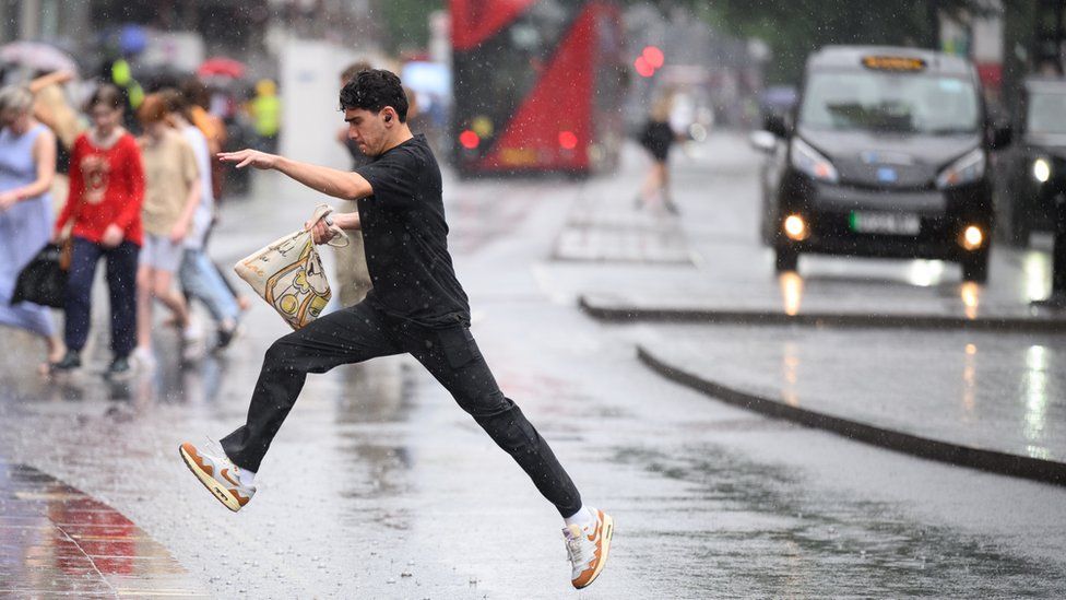 Man jumping over a puddle in London while crossing a road