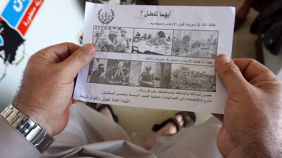 A Syrian man holds a leaflet dropped by the Syrian military over rebel-held Idlib province. It says: