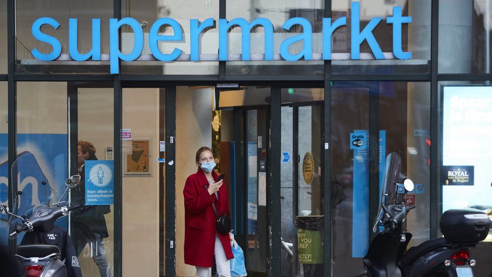A woman walks out a supermarket wearing a mask on October 14, 2020 in Amsterdam