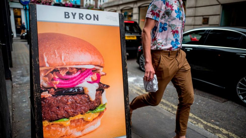 Мужчина проходит мимо вывески Byron Burger