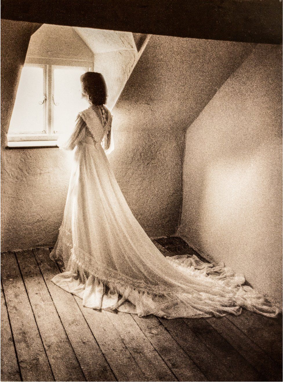 A woman looking out a window in a wedding dress