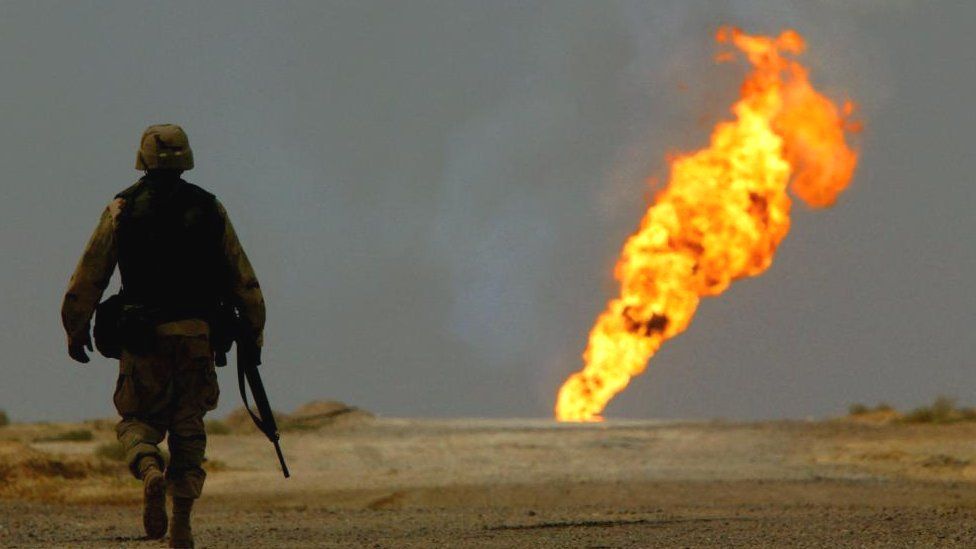 A US. Army soldier walks towards a burning oil well in Iraq's vast southern Rumaila oilfields