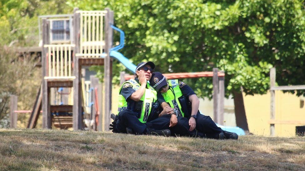 Two police officers comfort each other at the scene