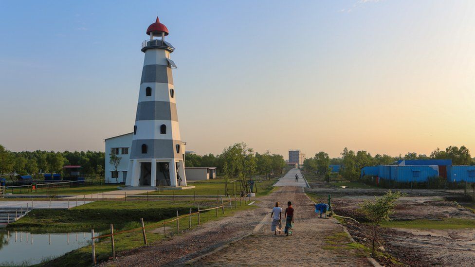 Bathed in evening sun, construction workers walk past the island's lighthouse