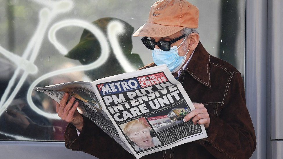 Man reads daily newspaper with mask on