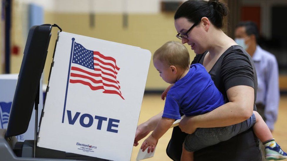 Избирательница голосует со своим ребенком в Александрии, штат Вирджиния