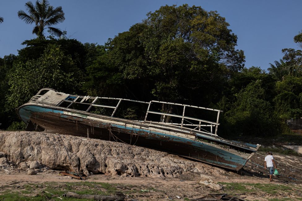 A man walks next to a boat in Manaus, Brazil, 07 October 2023