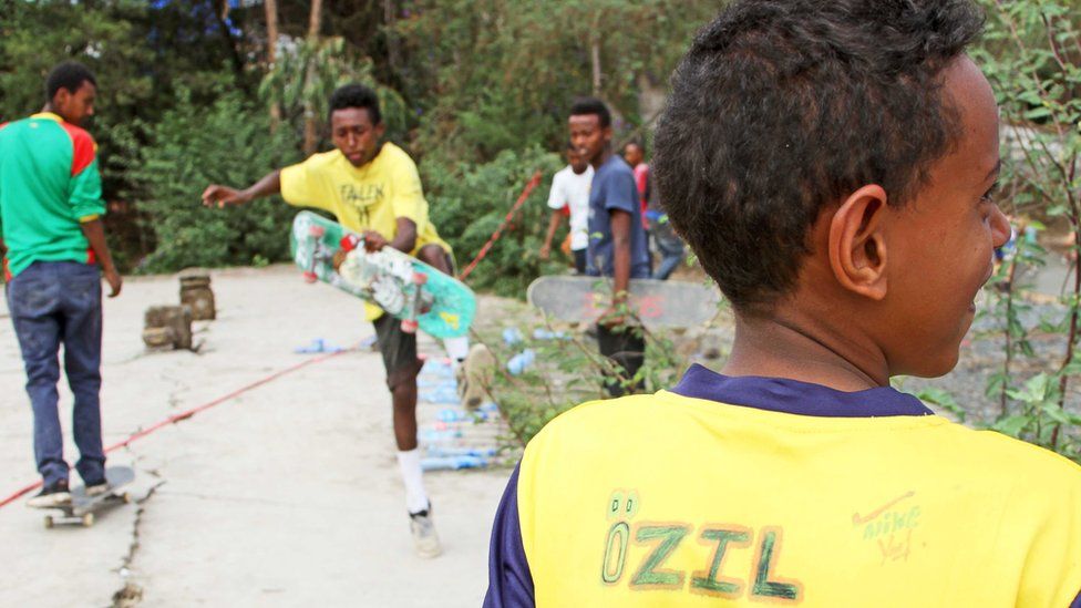 young boy runs with skateboard in his hand