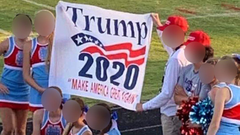 Cheerleaders pose with a President Trump banner
