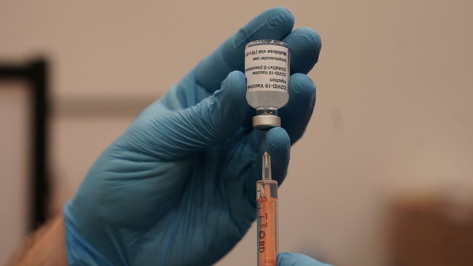 A vial of the Covid-19 vaccine being prepared by a healthcare worker