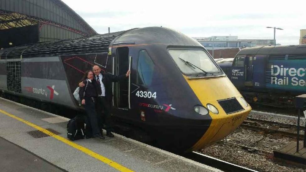 Zoe Loudon-Godfrey standing beside a colleague in the doorway of a Virgin Cross Country train parked at the station