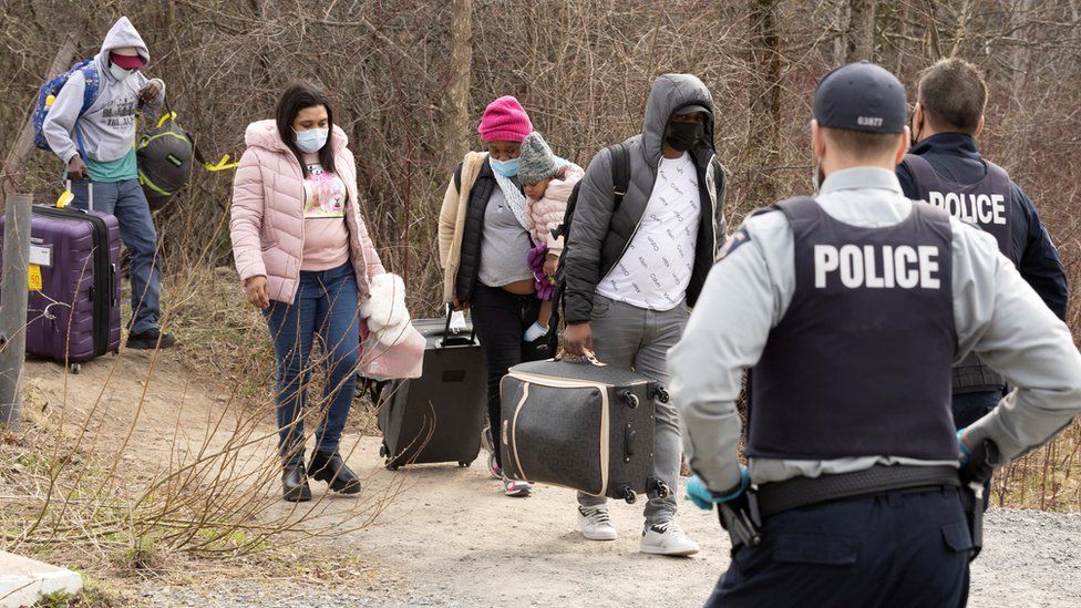 Asylum seekers cross into Canada from the US border near a checkpoint on Roxham Road near Hemmingford, Quebec in April 2022