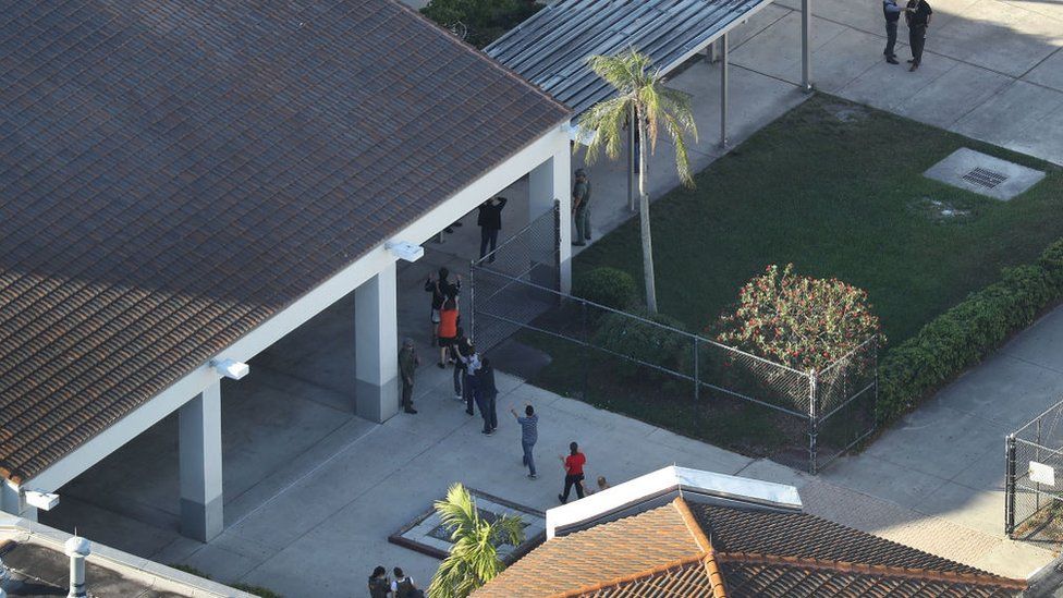 Se ve a personas siendo sacadas de la escuela secundaria Marjory Stoneman Douglas después del tiroteo el 14 de febrero de 2018 en Parkland, Florida.