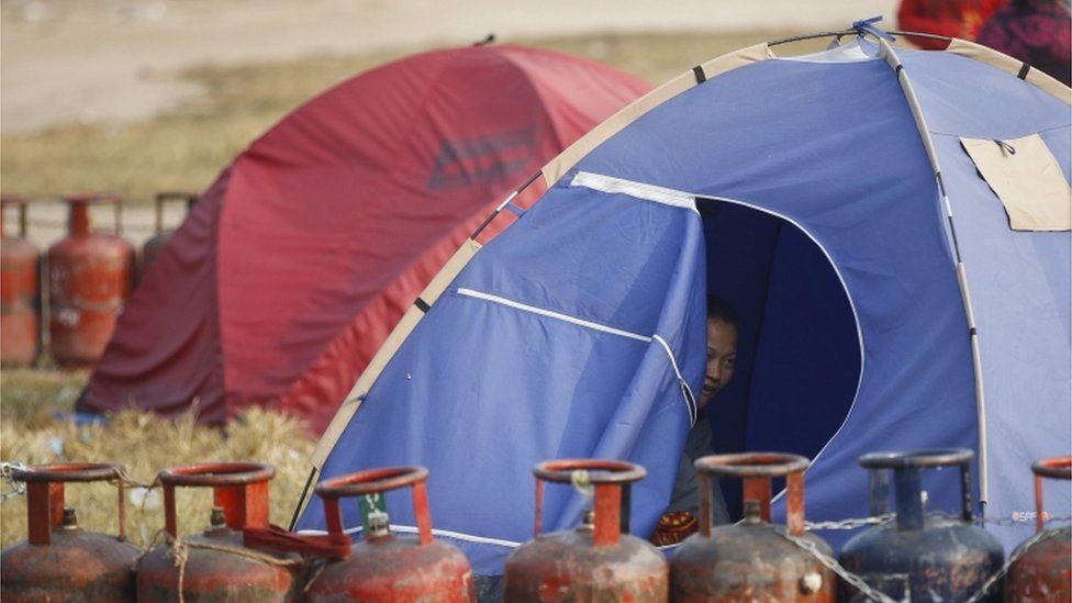 A Nepalese household looks on from her tent while waiting in a queue with their empty cooking gas cylinders for fresh supply in Kathmandu, Nepal, 18 November 2015.