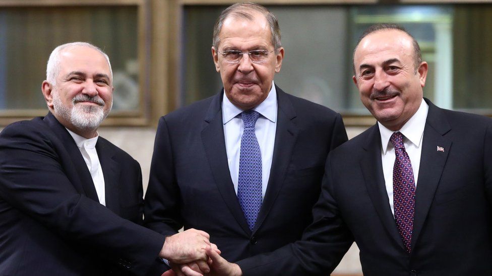 Iran's Foreign Minister Mohammad Javad Zarif (L), Russia's Minister of Foreign Affairs Sergei Lavrov (C), and Turkey's Minister of Foreign Affairs Mevlut Cavusoglu hold hands