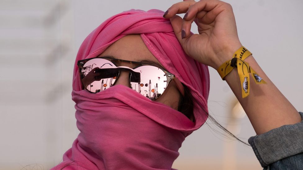 A woman in a pink head scarf with reflective sunglasses dances at the Dunes Electronique music festival in Ong Jmal, Tunisia - Saturday 16 November 2019