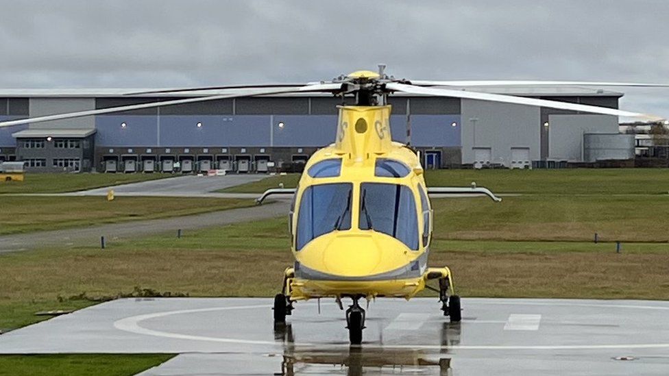 Yellow helicopter standing on the tarmac at a small airport