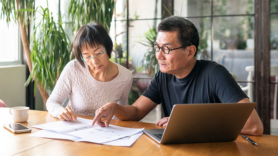 A couple look at a laptop and bills at home