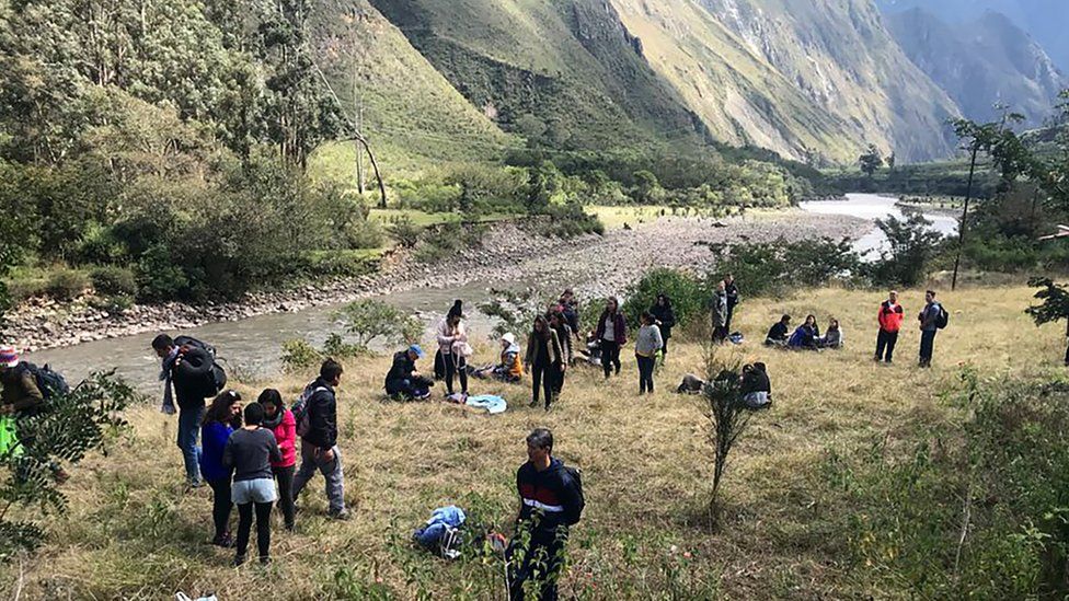 Passengers and crew stand along the railway track after two tourist trains crashed near the Inca citadel of Machu Picchu