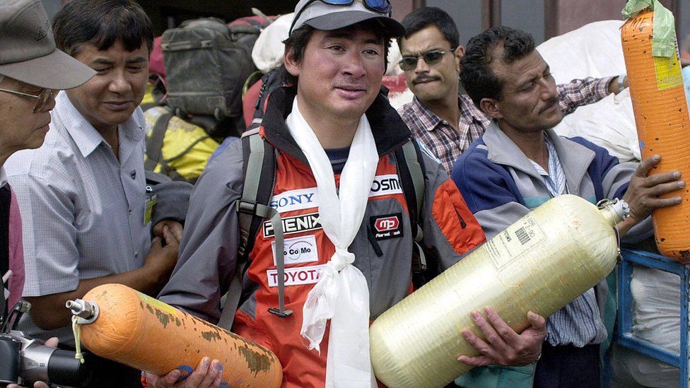 Leader of Everest clean up expedition Japanese mountaineer Ken Noguchi (C) holds empty oxygen bottles in Kathmandu airport, 23 May 2003