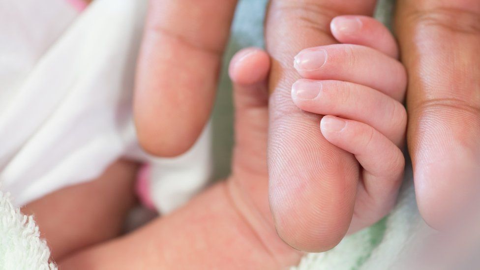 Newborn holding mother's hand
