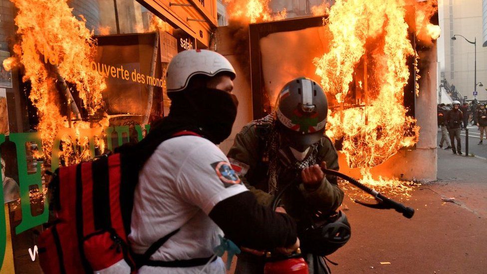 Firefighters try to extinguish the flames after protesters burn a billboard during a protest against the government's pension overhaul in Paris, France, January 11, 2020