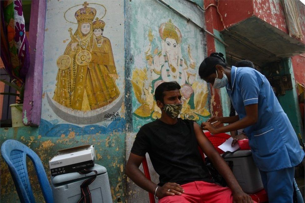 An Indian health worker administers a dose of the COVID-19 vaccine to a man in a residential area as part of a door-to-door COVID-19 vaccination campaign, in Chennai, India, 20 October 2021.