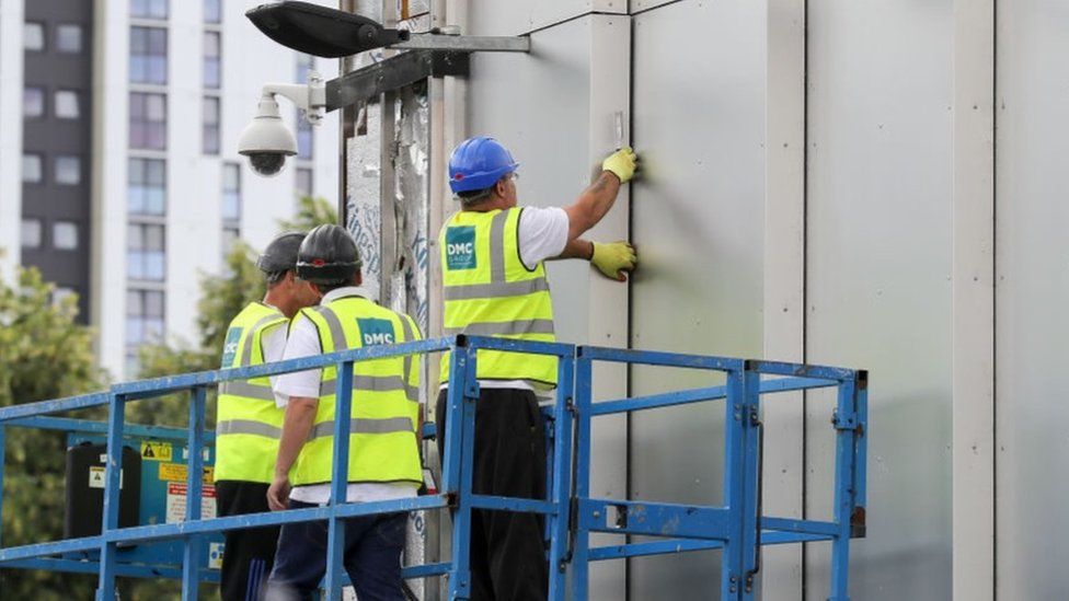 Workers removing cladding