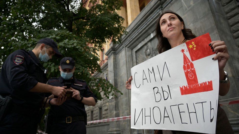 A protester against the designation holds up a sign outside the FSB building saying "foreign agents yourself"