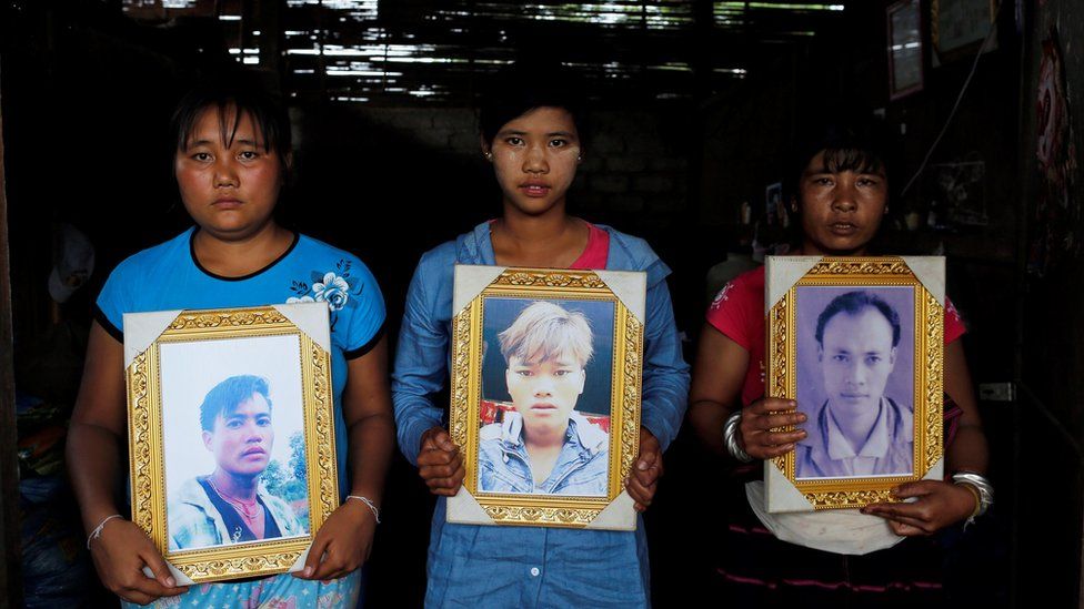 Villagers hold up pictures of the murdered men