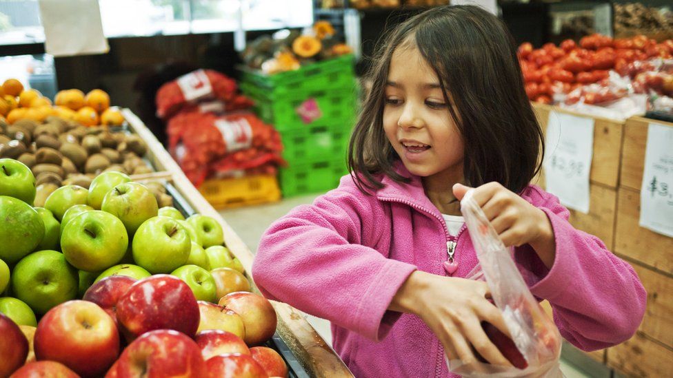 File photograph of child shopping for apples in a grocery store.