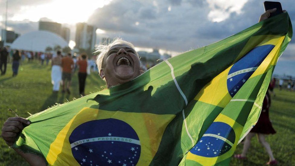 A supporter of Brazil's President Luiz Inacio Lula da Silva reacts holding a flag after gathering to listen to his speech at the Planalto Palace, in Brasilia, Brazil, January 1, 2023