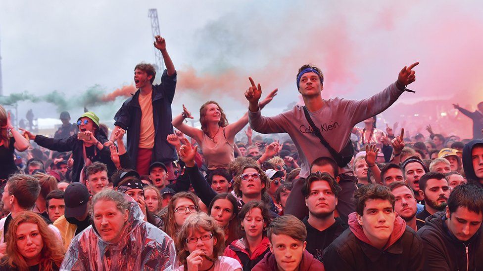 Festival-goers sitting on each others' shoulders in a crowd