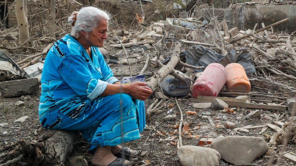 Woman sits amid the rubble of a bulding