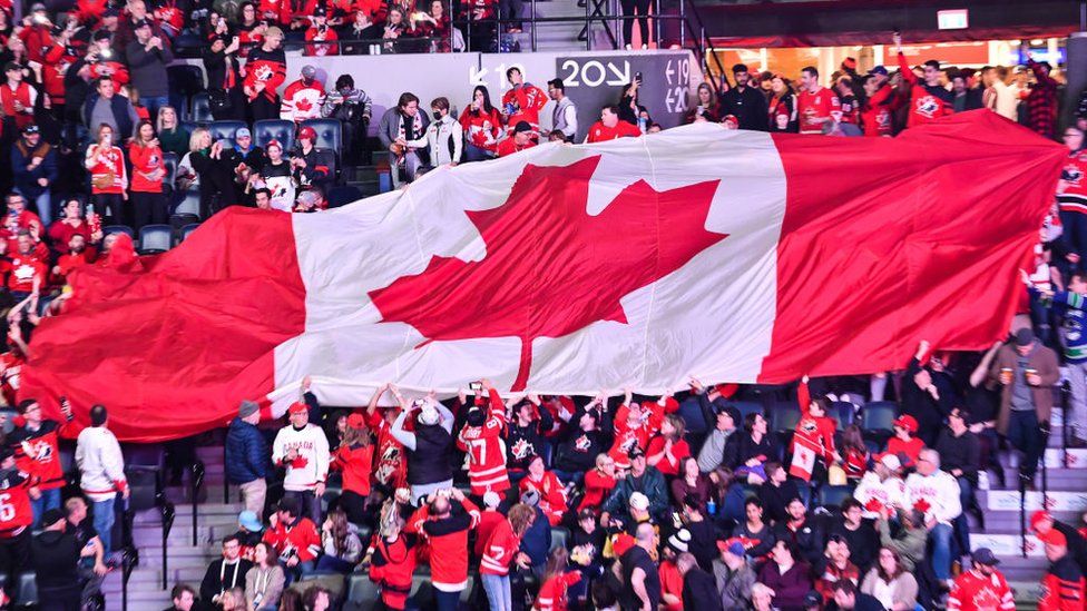 Fans in a stadium unfurl the Canadian flag