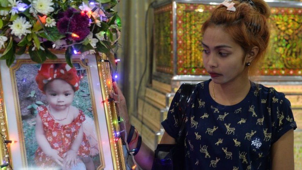 Jiranuch Trirat, mother of 11-month-old daughter who was killed by her father who broadcast the murder on Facebook, stands next to a picture of her daughter at a temple in Phuket.