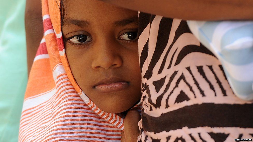 A child amongst a group of Sri Lankan asylum seekers sent back by Australia looks on before entering the magistrate's court in the southern port district of Galle on July 8, 2014