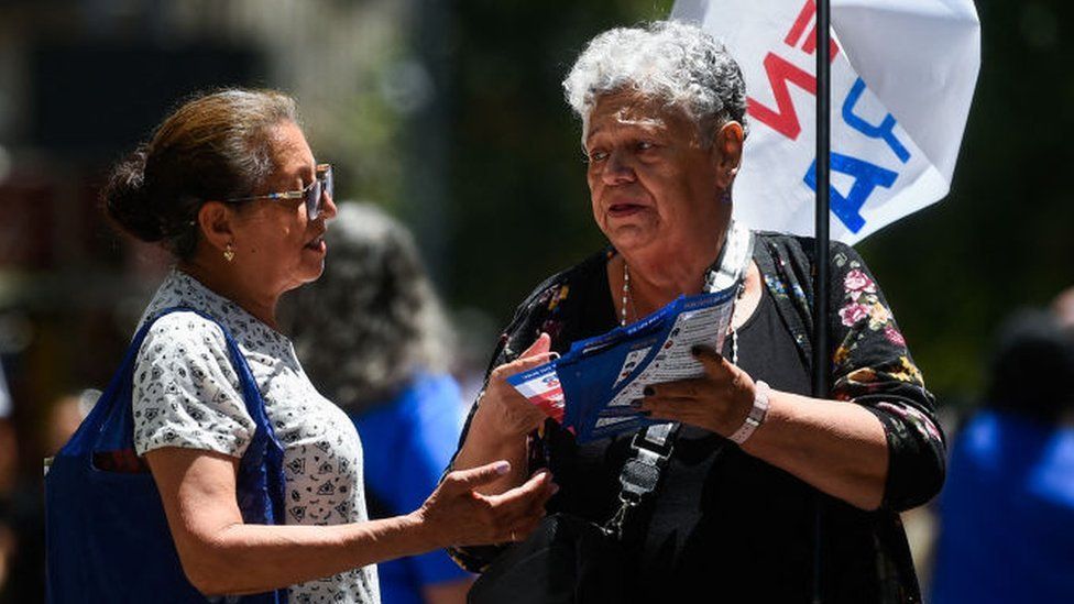 A supporter of the "En Contra (Against)" option for Chile's constitution proposal hands out flyers in Santiago on December 12, 2023.