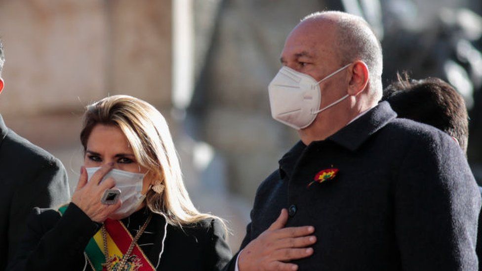 Interim President of Bolivia Jeanine Añez wearing a face mask stands next to Minister of Government Arturo Murillo (R)