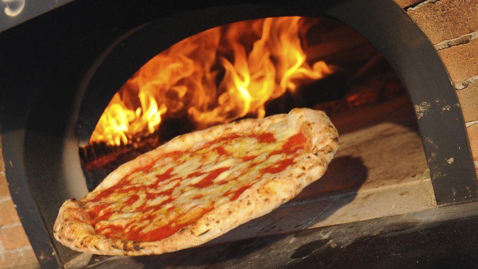 A pizza going into a pizza oven
