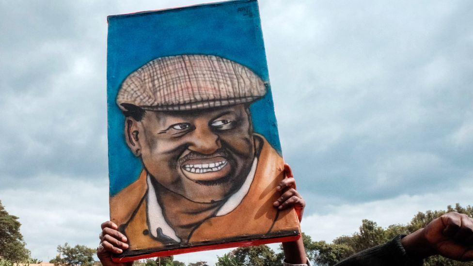A portrait of Raila Odinga being held aloft at a campaign rally - Kenya 2022