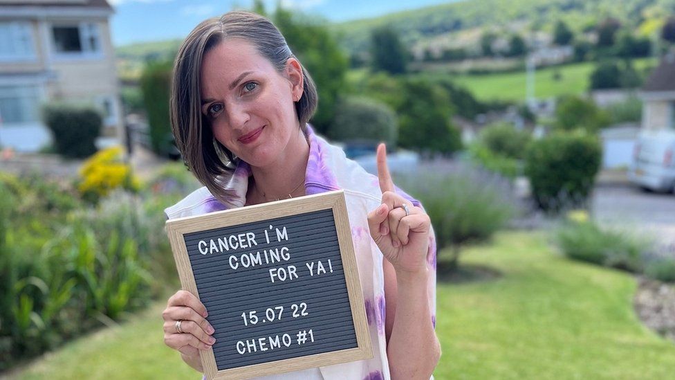 Portrait of Jessica Parsons holding a sign saying: "Cancer I'm coming for ya!"