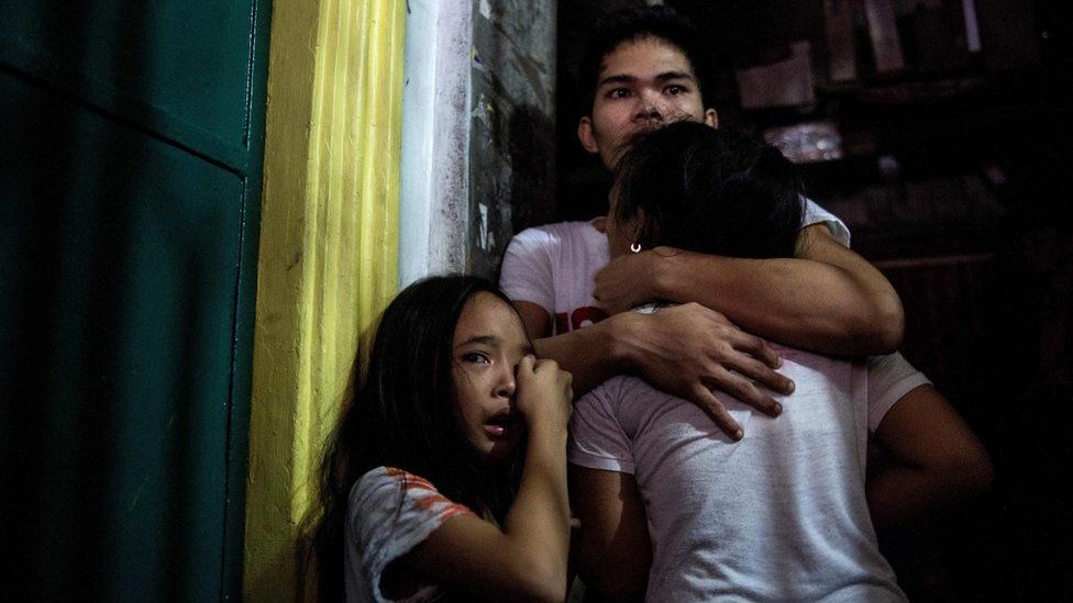 This picture taken on 5 January 2017, shows relatives crying as coroners carry away the body of an alleged drug dealer killed during a drug buy bust operation in Manila