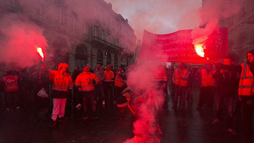 French union members light flares as they protests against planned labour reforms