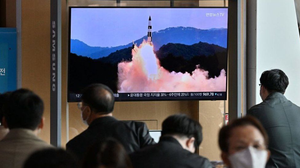Люди смотрят телевизионный экран, на котором транслируется выпуск новостей с записью испытания северокорейской ракеты,