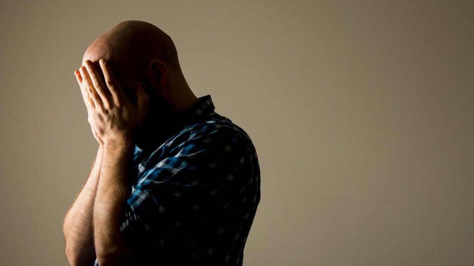 Stock shot of a man holding his head in his hands