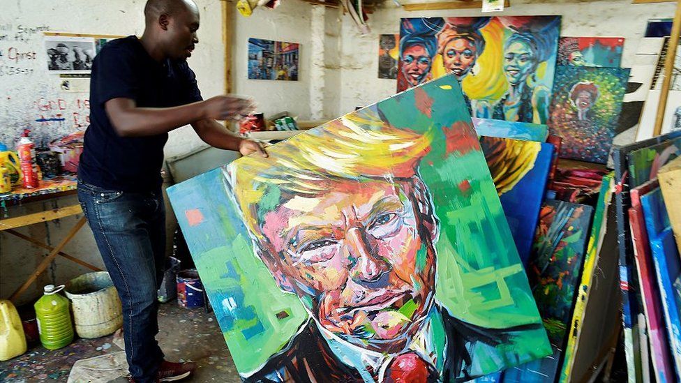 Kenyan artist Evans Yegon aka 'Yogonizer' carries one of his painting of USA President-elect Donald Trump at his workshop December 15, 2016 at the GoDown art Centre in Nairobi