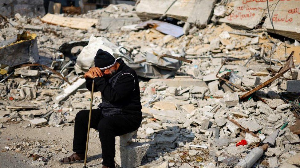 A man sits in front of the rubble of a house in Rafah, in the south of the Gaza Strip